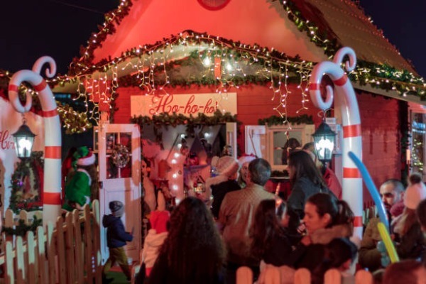 coda di persone in attesa di entrare nella casa illuminata di Babbo Natale