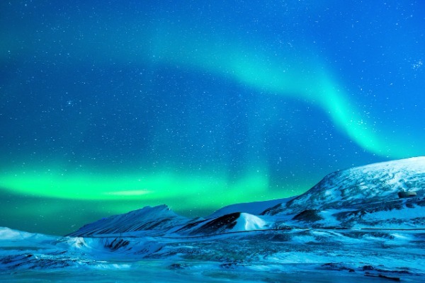 paesaggio innevato con aurora boreale e cielo stellato